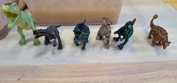 muddy dinosaur sensory play activity in a sensory bin
