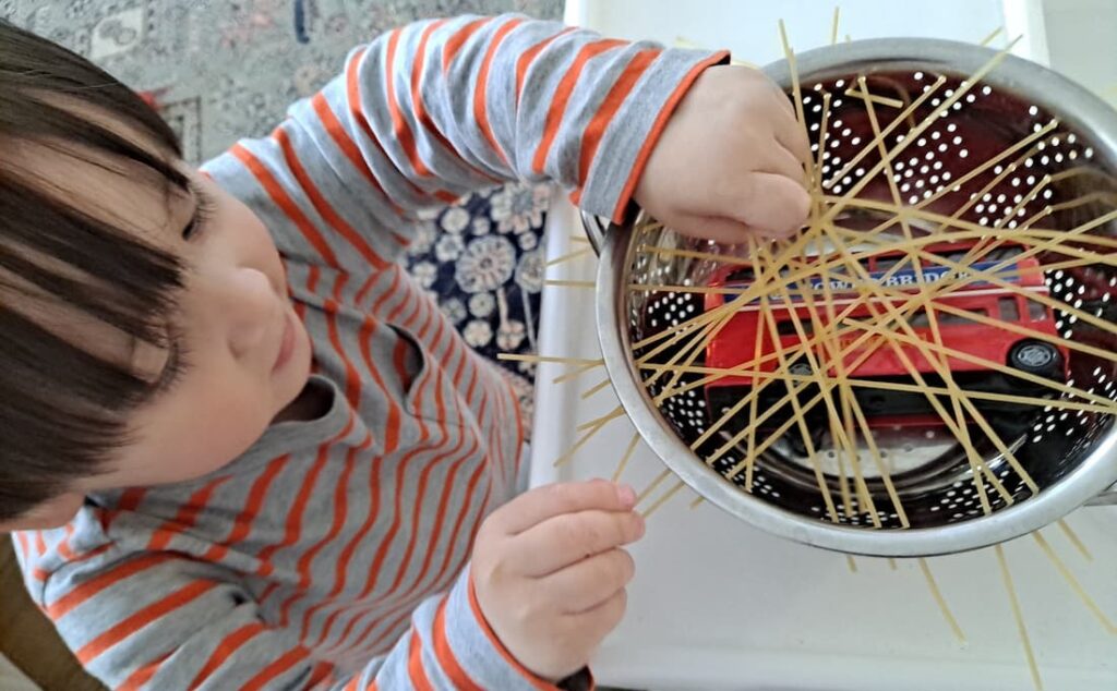 easy fine motor activity for toddlers rescue toy bus stuck in spaghetti colander