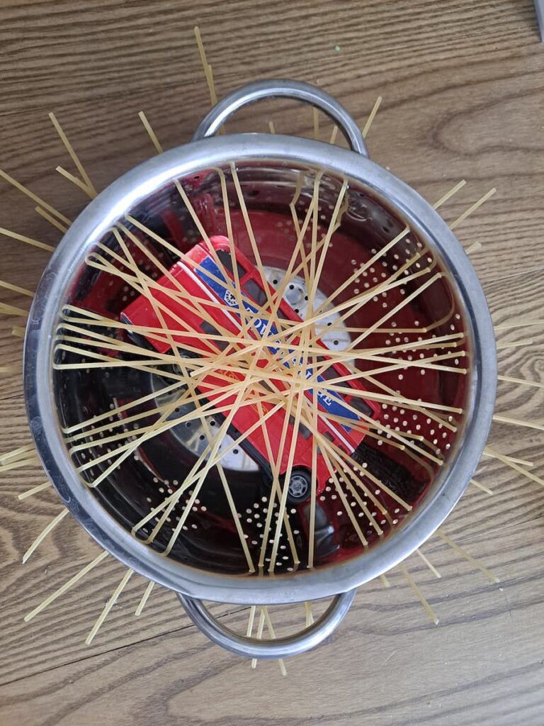 easy fine motor activity for toddlers rescue toy bus stuck in spaghetti colander