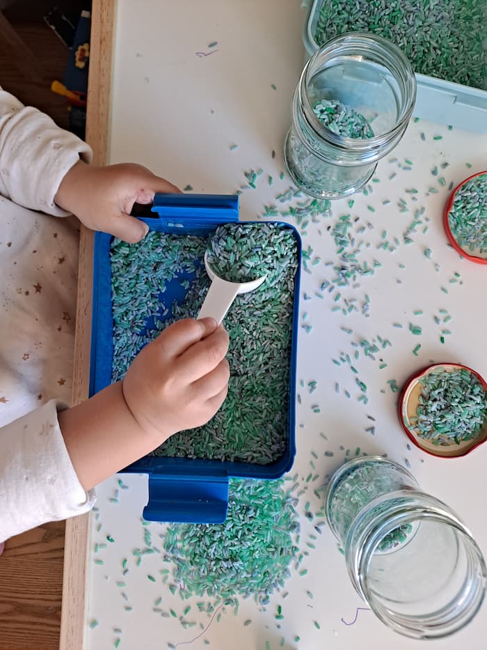 toddler scooping colored rice activity