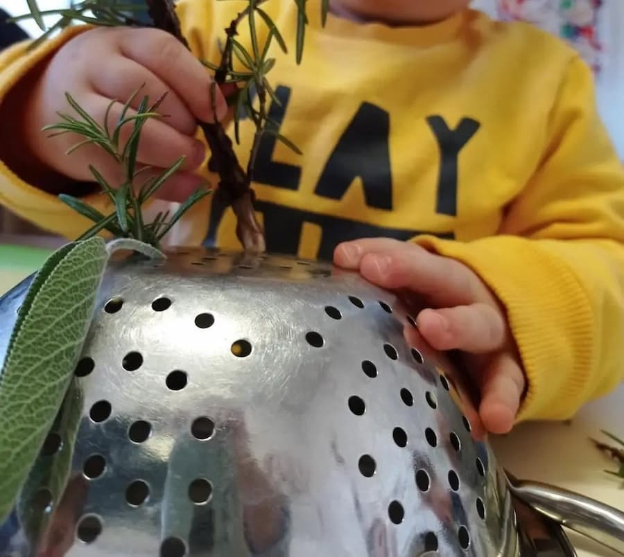 toddler fine motor activity with colander and sticks